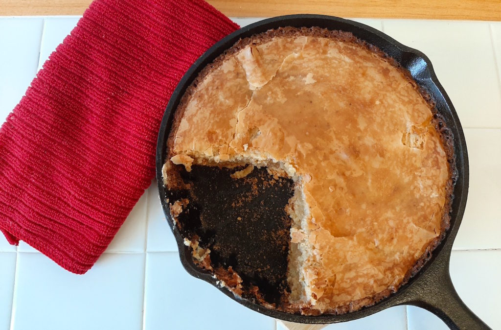 Sliced Gooey Brown Butter cake in a small cast iron skillet with red dish towel. Pairs well with Edradour 10.