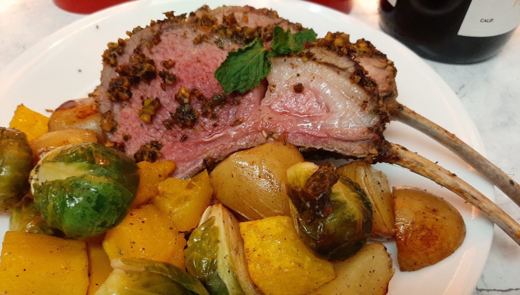 Roasted Lamb Rack, crusted with pistachios and mint on a bed of roasted brussels sprouts, butternut squash, and potatoes. Rare Lamb.