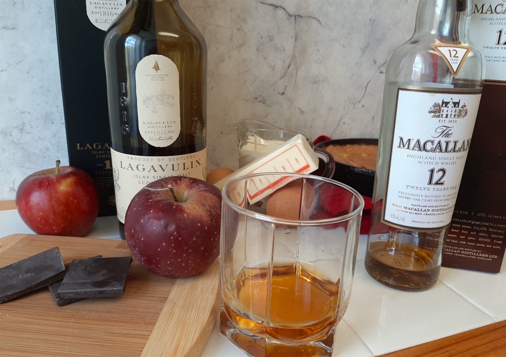 Lagavulin 16 and Macallan 12 with gooey brown butter cake, apples, dark chocolate, and creme brulee ingredients in a kitchen.