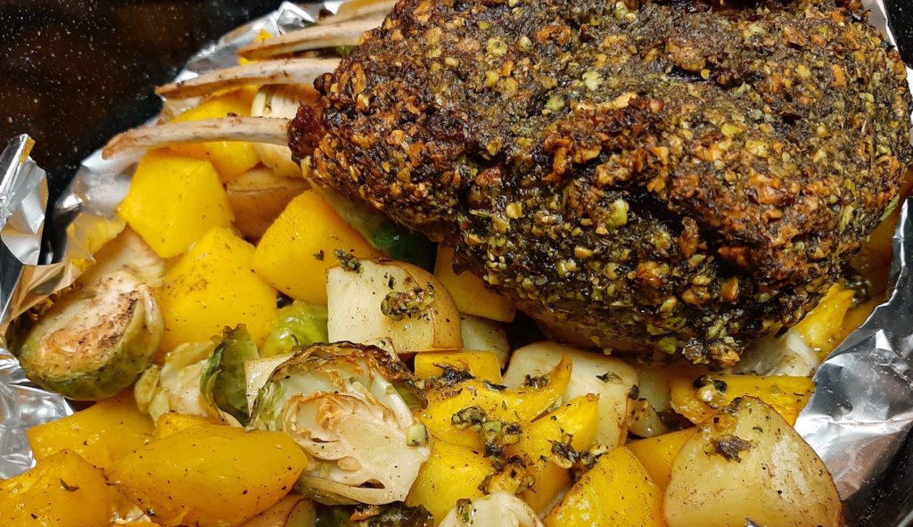 Roasted Whole Half Lamb Rack, crusted with pistachios and mint on a bed of roasted brussels sprouts, butternut squash, and potatoes just out of the oven.