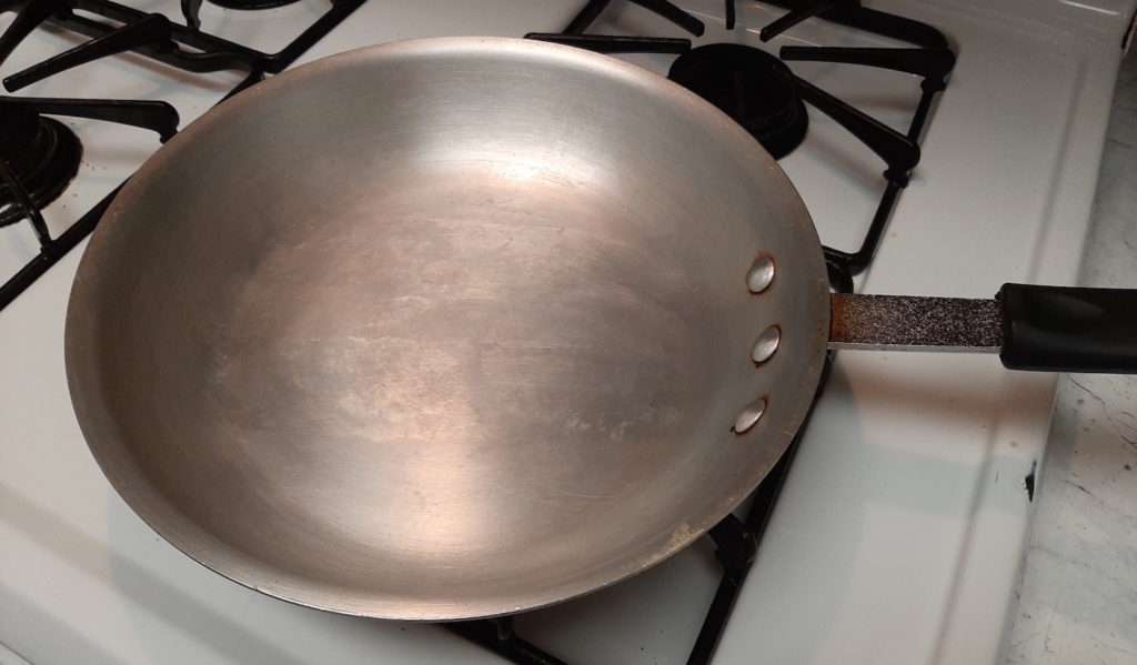 Stainless steel pan for searing on a gas stove.