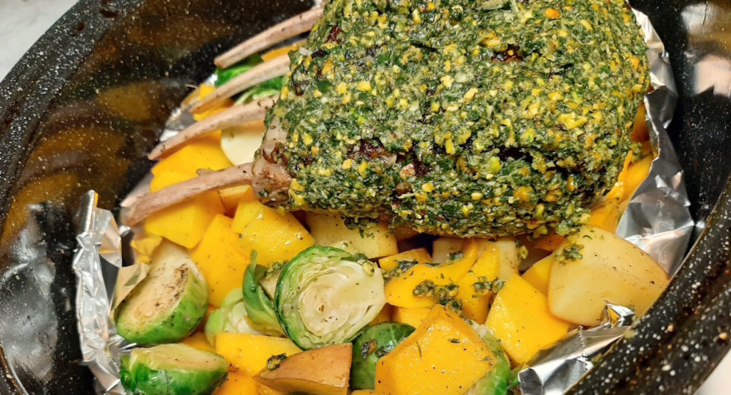 Whole Half Rack of Lamb, crusted with pistachios and mint on a bed of roasted brussels sprouts, butternut squash, and potatoes. Ready to go in the oven.