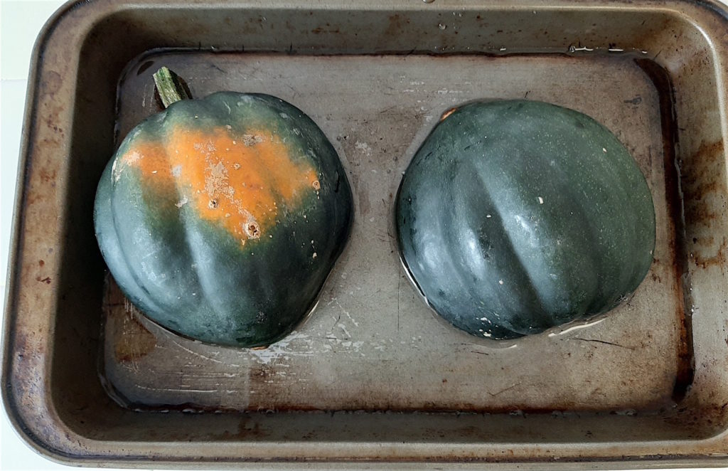 Whole Acorn Squash roasting in a tin of water