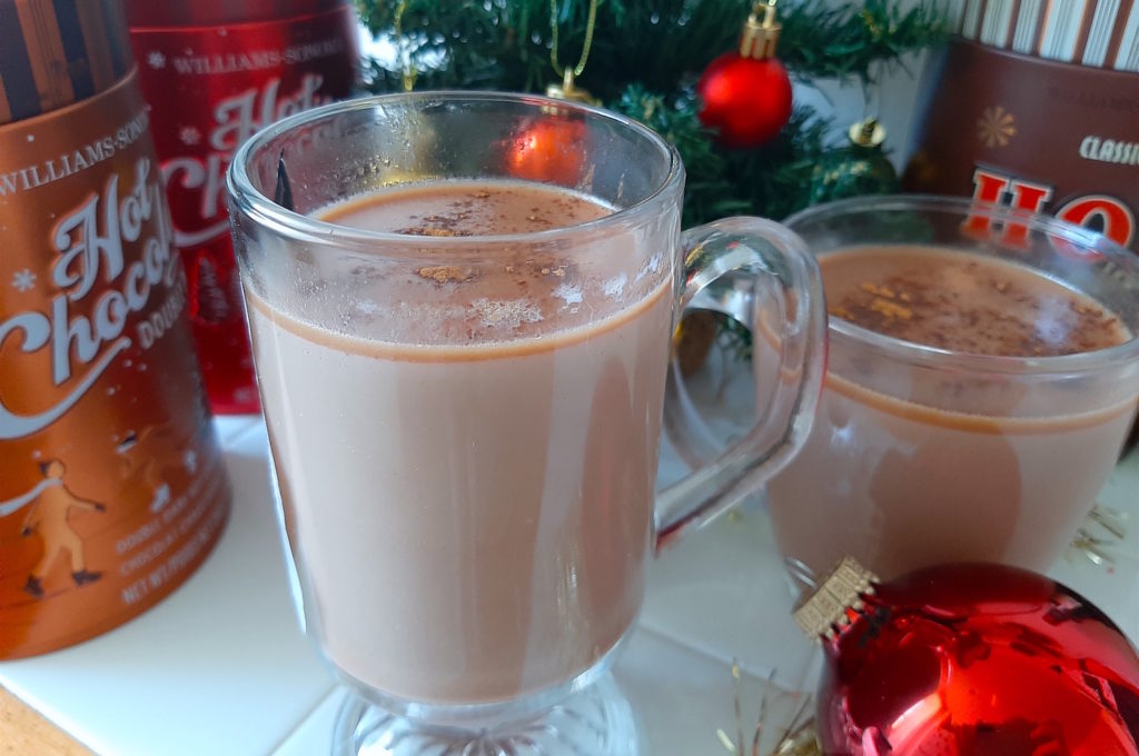Spiked Hot Chocolate with rum and whisky with Christmas tree and ornaments. Decorative hot chocolate containers. Christmas cocktails.