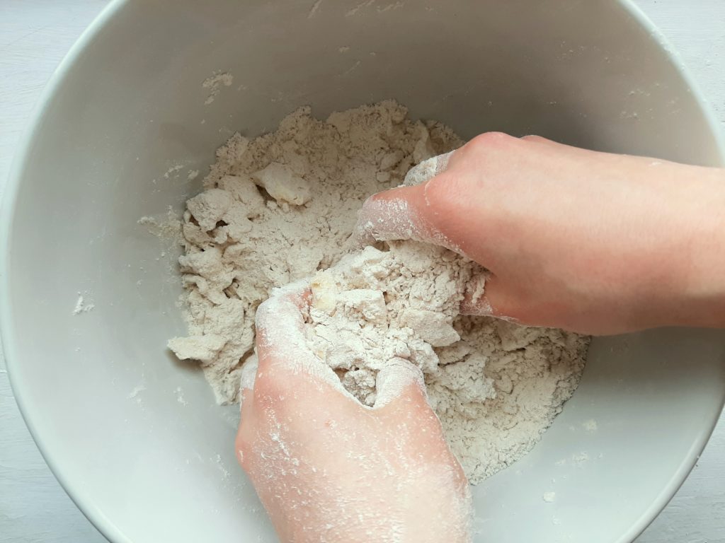 Hands mixing butter and flour for spiced all-butter pie crust. Sugar with Spice Blog