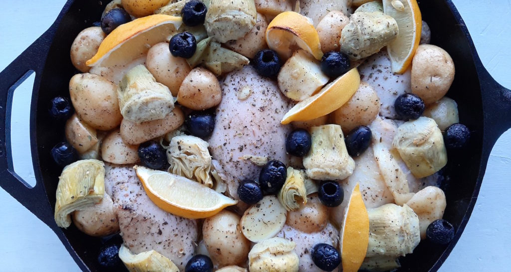 Oven Roasted Chicken Thighs with Potatoes, Artichokes, Olives, Lemon, Wine and Chicken Broth in a large Cast Iron Skillet