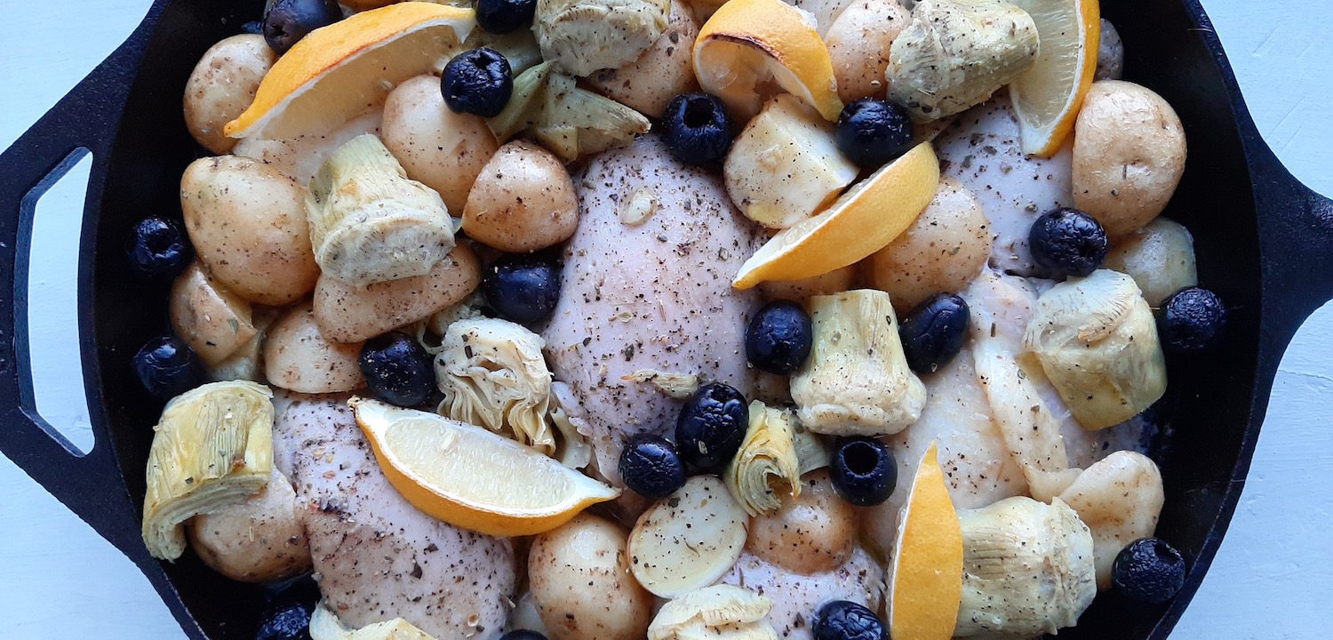 Oven Roasted Chicken Thighs with Potatoes, Artichokes, Olives, Lemon, Wine and Chicken Broth in a large Cast Iron Skillet