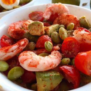 Fresh protein salad with edamame beans, fresh tomatoes, fresh avocado, lightly steamed shrimp and paprika and lime in a white bowl. Sugar with Spice Blog.