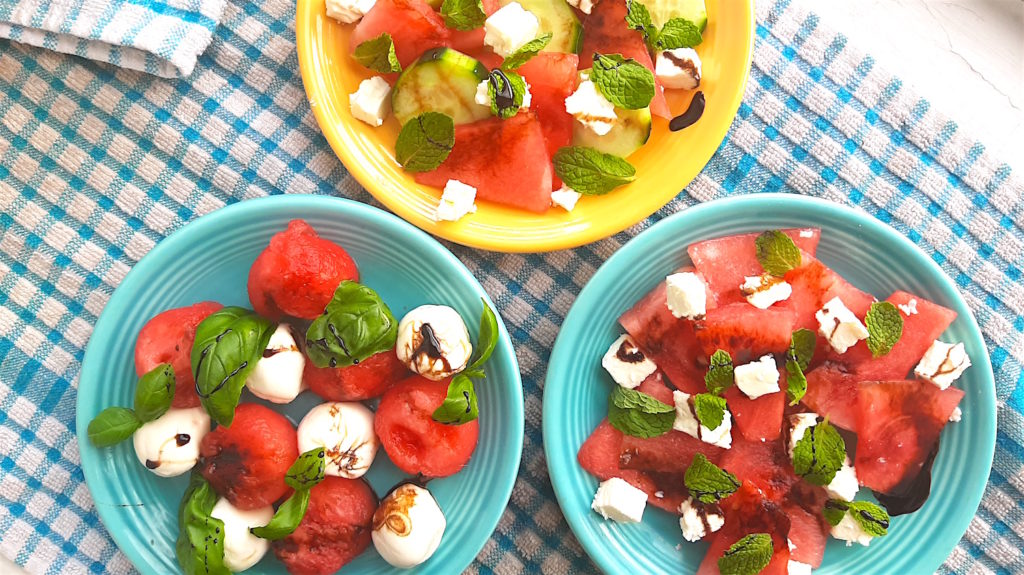 Three Watermelon Salads on blue and yellow plates over a blue checked cloth, overhead shot. Watermelon with basil and mozzarella or cucumber, mint, and feta. Drizzled with balsamic reduction glaze. Sugar with Spice Blog.