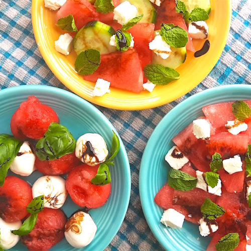 Three Watermelon Salads on blue and yellow plates over a blue checked cloth, overhead shot. Watermelon with basil and mozzarella or cucumber, mint, and feta. Drizzled with balsamic reduction glaze. Sugar with Spice Blog.