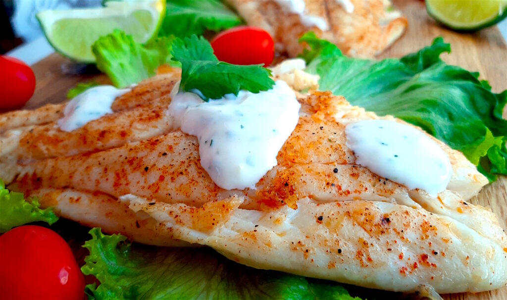 Pan-Seared Red Snapper with paprika seasoning and creamy cilantro lime sauce served on a bed of lettuce and tomatoes. Sugar with Spice Blog.