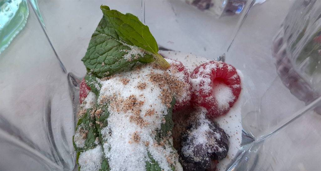 Mixed Berry Mojito ingredients in a tumbler. Fresh raspberries and blackberries and mint leaves in a glass with sugar and ground cardamom. Sugar with Spice Blog