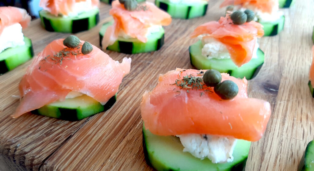 Cucumber Smoked Salmon Bites on a wooden cutting board with boursin cheese, capers, and smoked salmon. Close Up shot. Sugar with Spice Blog.