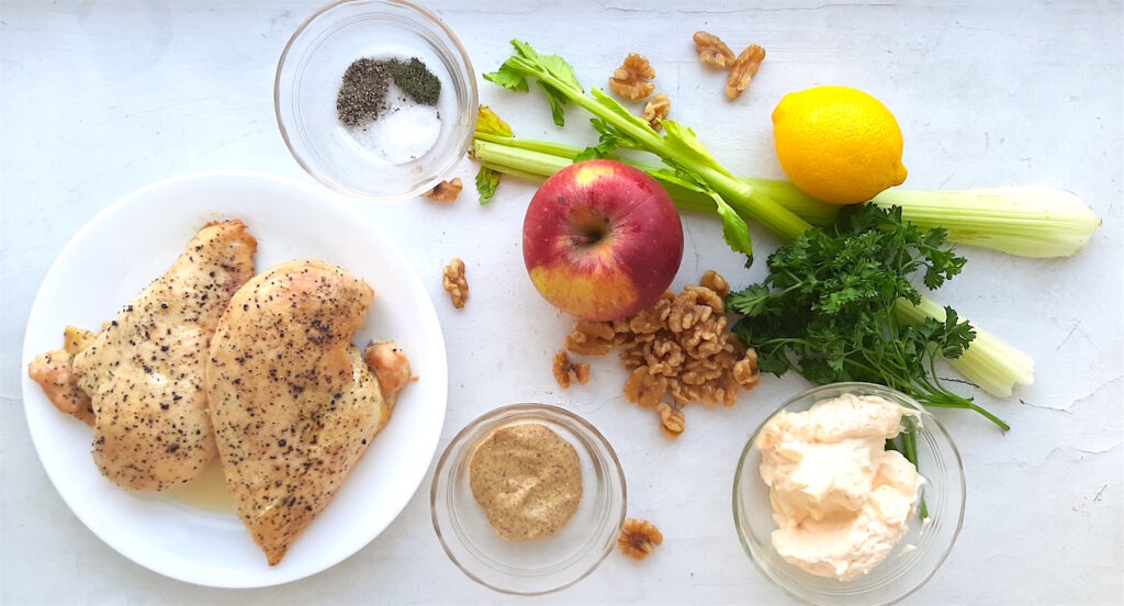 Chicken Salad with Apples and Walnuts ingredients on a white background: celery, apples, lemons, parsley, walnuts, mustard, mayonnaise, seasonings , and fresh chicken. Sugar with Spice Blog.