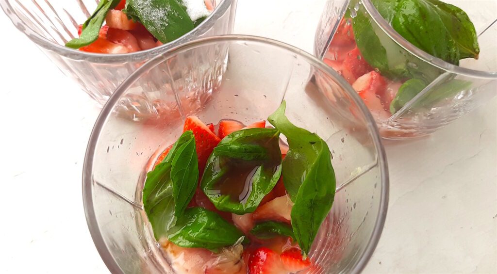 Balsamic Strawberry Basil Mojito ingredients in three tumblers to be muddled: fresh strawberries, balsamic vinegar, fresh basil, sugar, rum, and tonic water. Overhead shot. Sugar with Spice Blog.