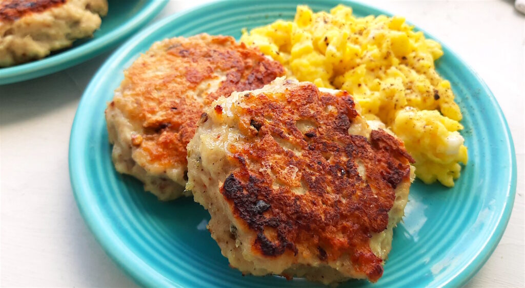 Homemade turkey sausages on a blue plate with creamy scrambled eggs on a white window sill. Close up shot. Sugar with Spice Blog.