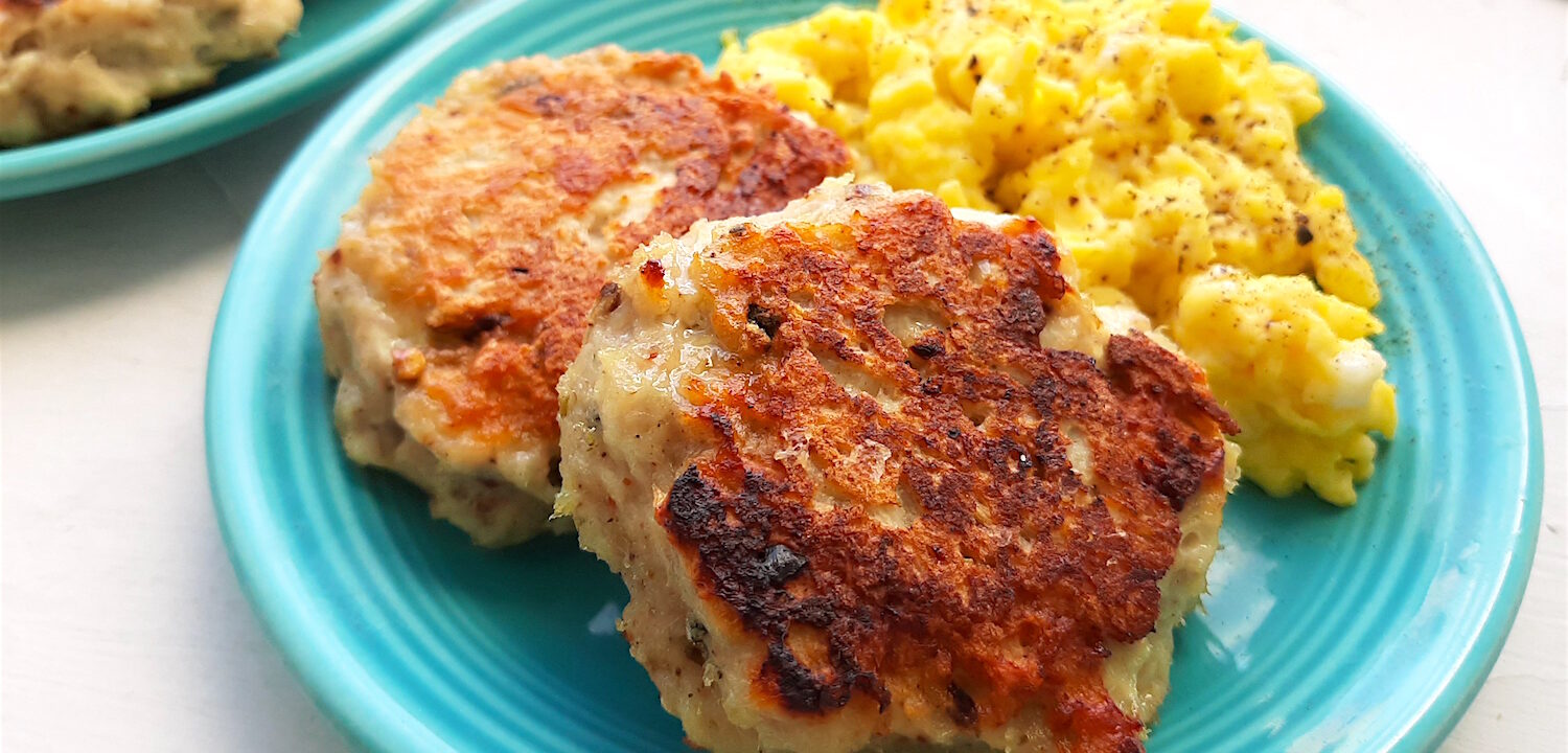 Homemade turkey sausages on a blue plate with creamy scrambled eggs on a white window sill. Close up shot. Sugar with Spice Blog.