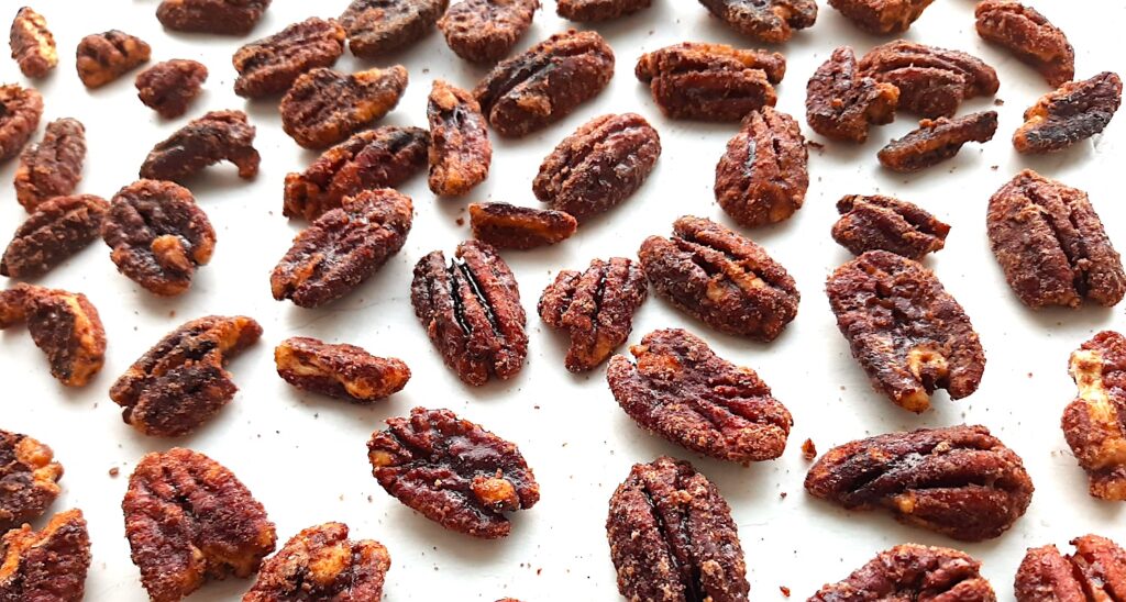 Maple candied pecans drying on a white background. Front shot. Sugar with Spice Blog.