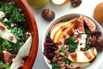 Winter Pear Salad in a white ceramic bowl bowl, ingredients separated including: sliced d'anjou pears, sliced bosc pears, gorgonzola, dried cranberries, quartered figs, sautéed pancetta, maple candied pecans, and kale. Drizzled with cranberry balsamic dressing. More winter pear salad, tossed, in a wooden bowl to the left, half in frame. Fresh d'anjou pears, bosc pear, mission fig, maple candied pecans, and dried cranberries surround. All on a white background. Overhead shot. Sugar with Spice Blog.