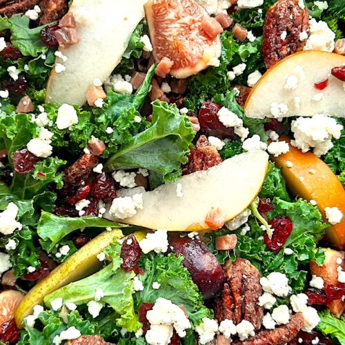 Winter Pear Salad in a brown wooden bowl including: sliced d'anjou pears, sliced bosc pears, gorgonzola, dried cranberries, quartered figs, sautéed pancetta, maple candied pecans, and kale. All on a white background. Overhead shot. Sugar with Spice Blog.
