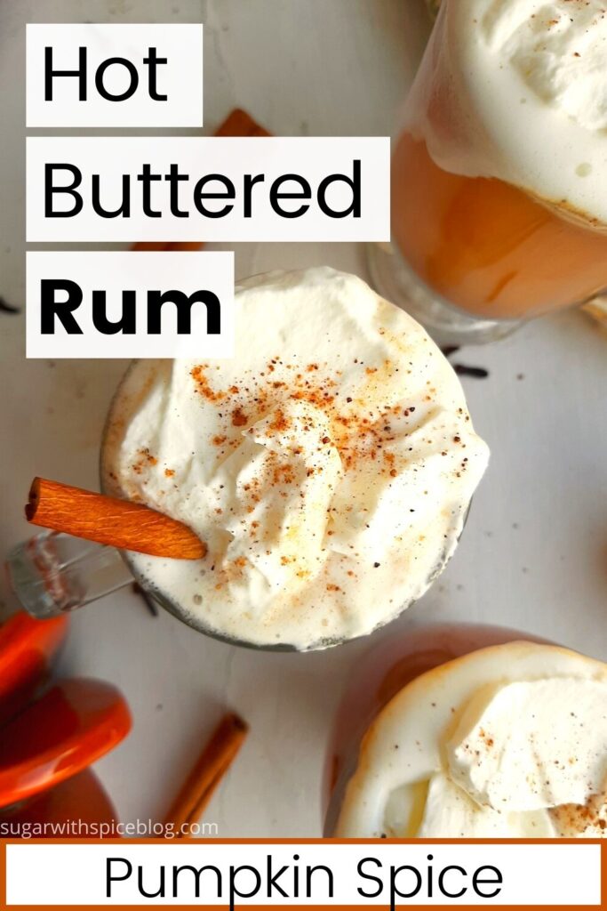 Three glasses of pumpkin spice hot buttered rum topped with whipped cream, cinnamon sticks, and ground nutmeg on a white windowsill. Window sill decorated with ceramic pumpkins, whole cloves, whole cinnamon sticks, and ground nutmeg. Overhead shot. Sugar with Spice blog. Pinterest Image. Black text on white background paneling says "Hot Buttered Rum Pumpkin Spice."